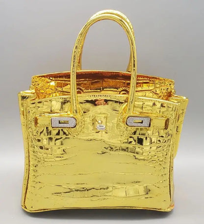 Gold handbag with crocodile pattern on a grey background Sculptural vase for dried flowers