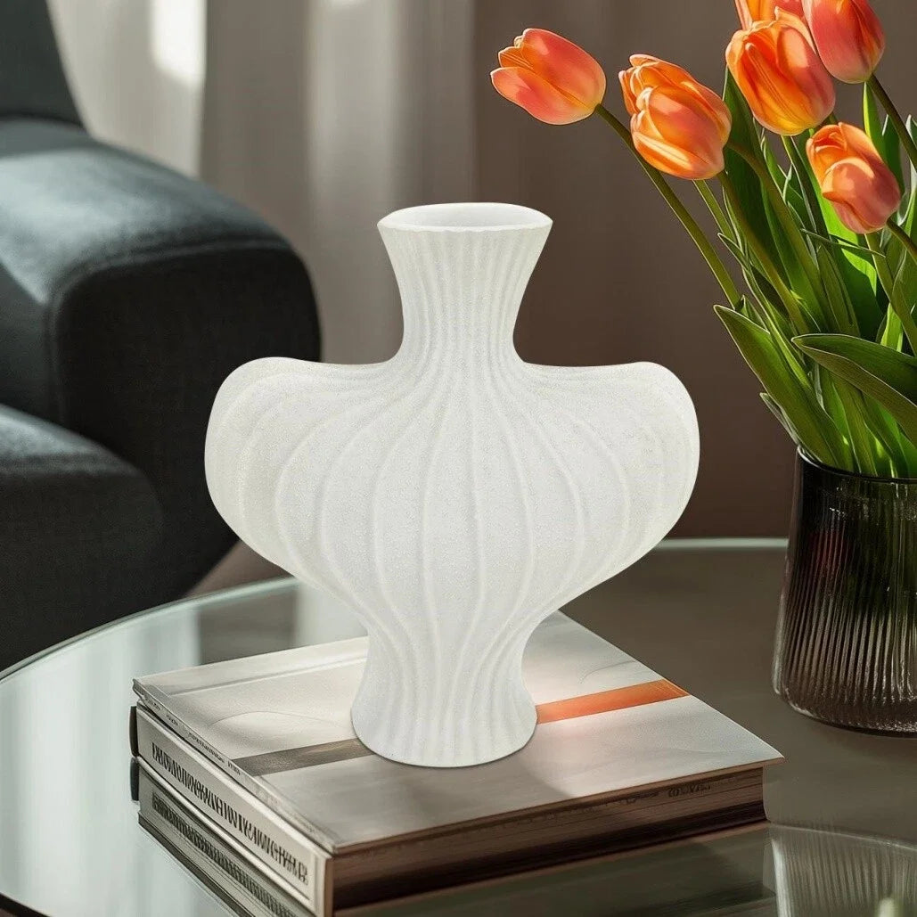 White textured vase on a stack of books with orange tulips in the background
