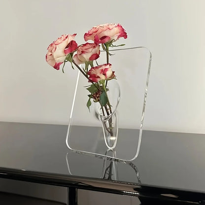 Clear glass vase with pink roses on a reflective surface