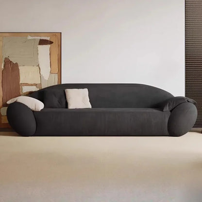 Modern black sofa with white cushions in a minimalistic room.