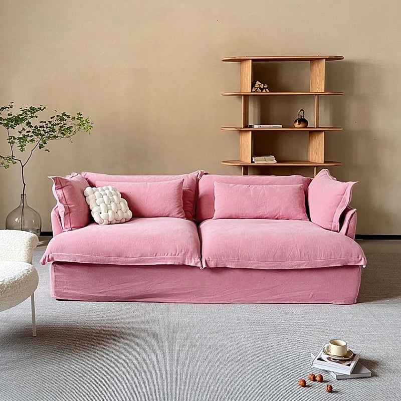 Pink sofa in a room with a wooden shelf and decorative items.