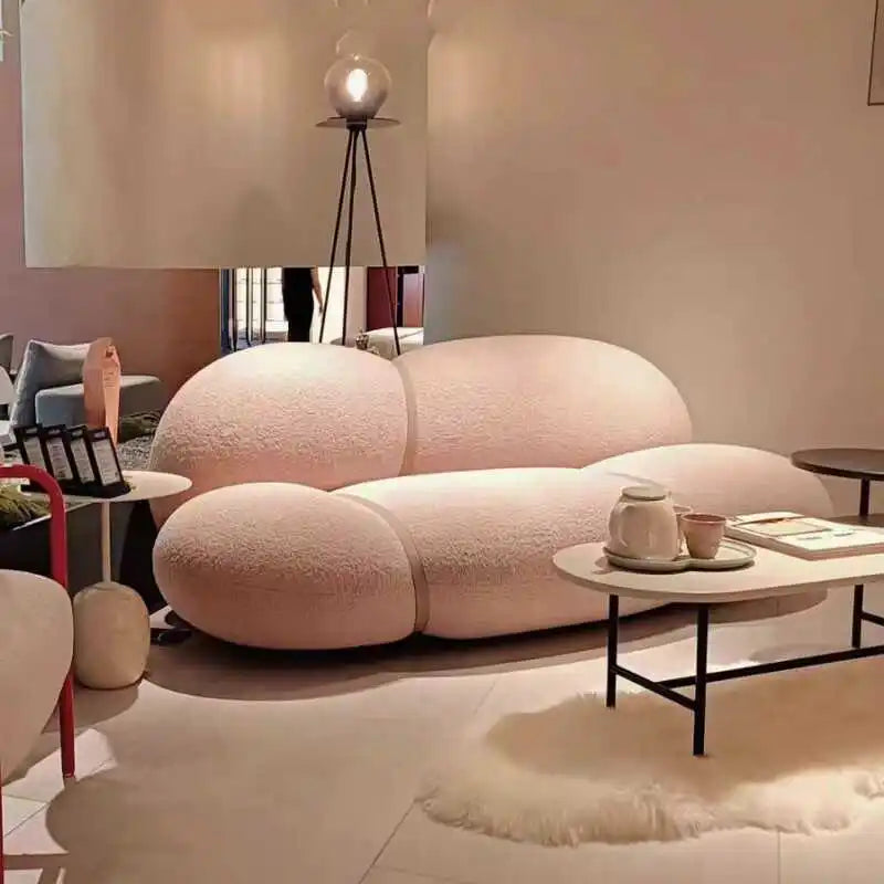 Modern living room with a pink, futuristic sofa and a small round table.