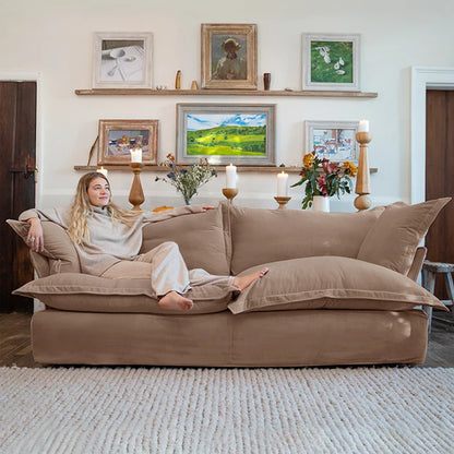 Woman relaxing on a beige sofa in a living room with framed pictures and decor.