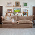 Woman relaxing on a beige sofa in a living room with framed pictures and decor.