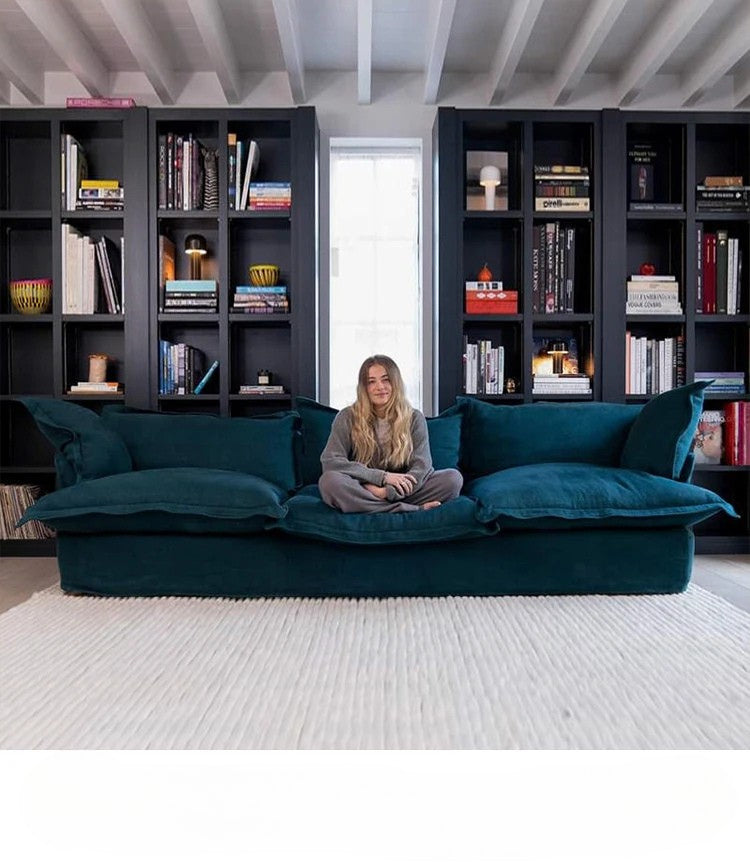 Woman sitting on a teal sofa in a room with bookshelves.