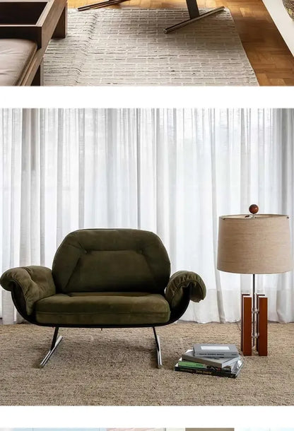 Green armchair in a living room with a lamp and books on a table.
