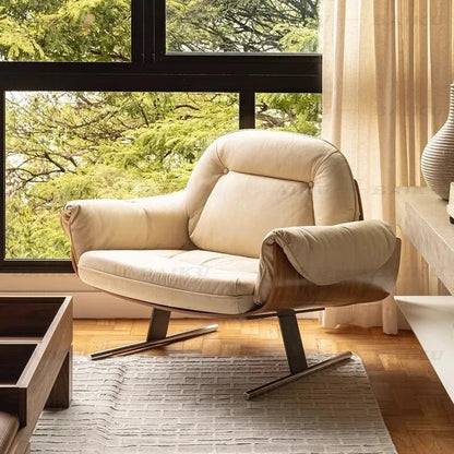 Beige armchair in a living room with large windows and curtains