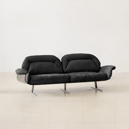 Black sofa on a light wooden floor with a white wall background