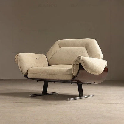 Beige armchair with a wooden base on a wooden floor against a plain wall.