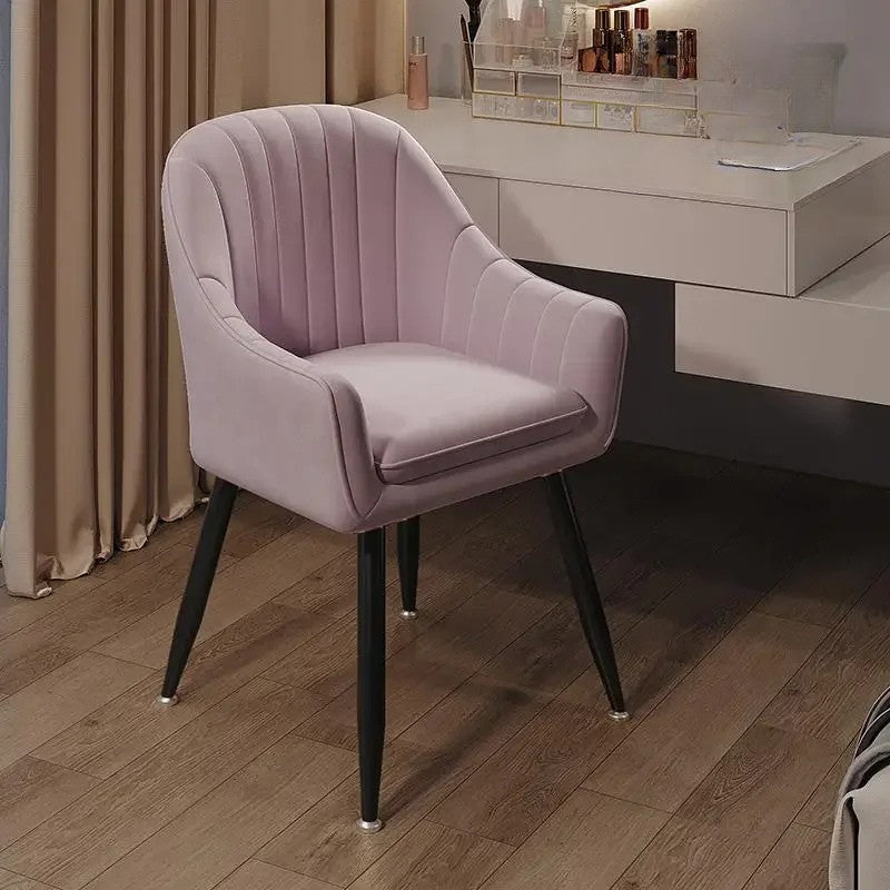 Pink velvet chair on a wooden floor with a blurred background