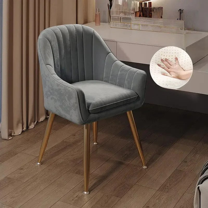 Gray velvet chair with gold legs on a wooden floor, close-up of fabric texture shown.