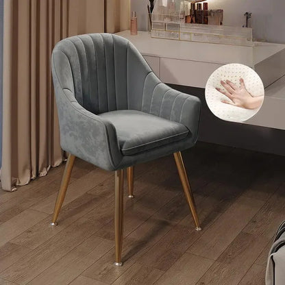 Gray velvet chair with gold legs on a wooden floor, close-up of fabric texture shown.