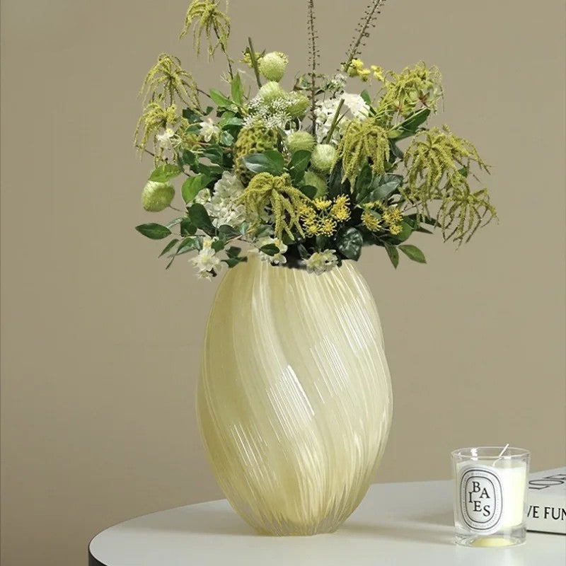 Decorative vase with green floral arrangement on a table against a beige wall
