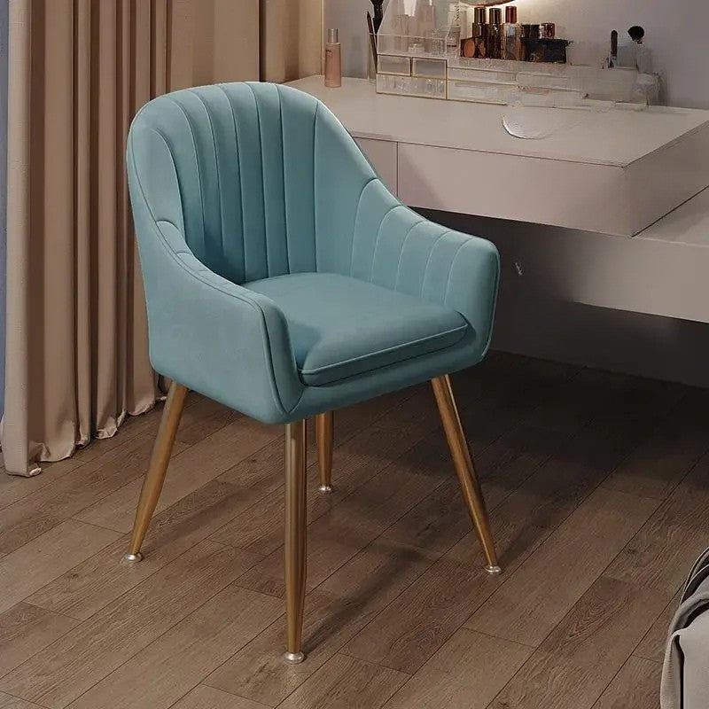 Teal chair with gold legs on a wooden floor in a room setting.