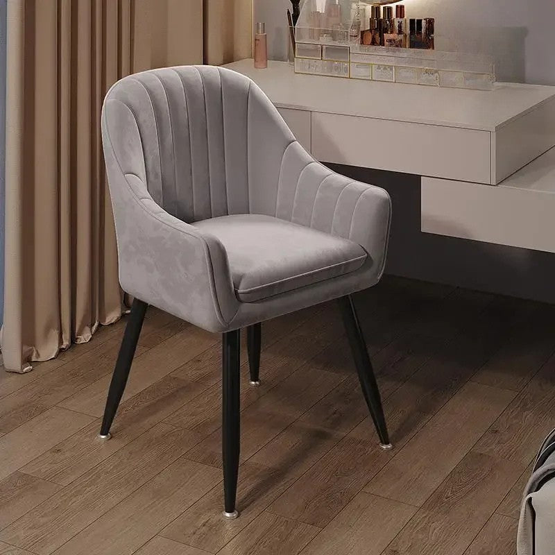 Gray velvet chair on a wooden floor with a blurred background