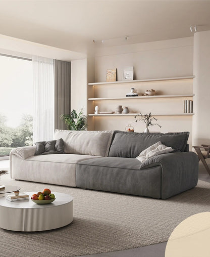 Modern living room with a gray sectional sofa, round coffee table, and shelves.
