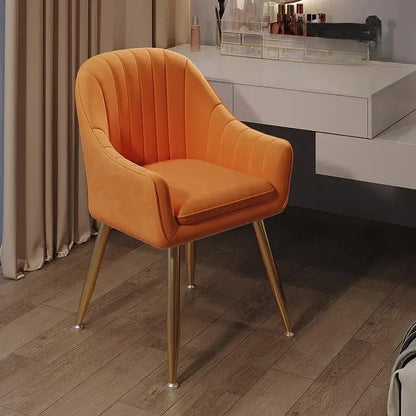 Orange chair with gold legs on a wooden floor in a room setting.