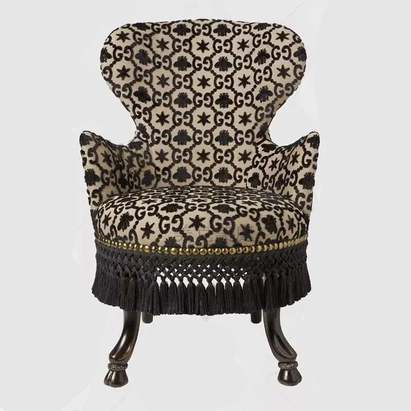 Decorative armchair with patterned fabric and black fringe on a white background