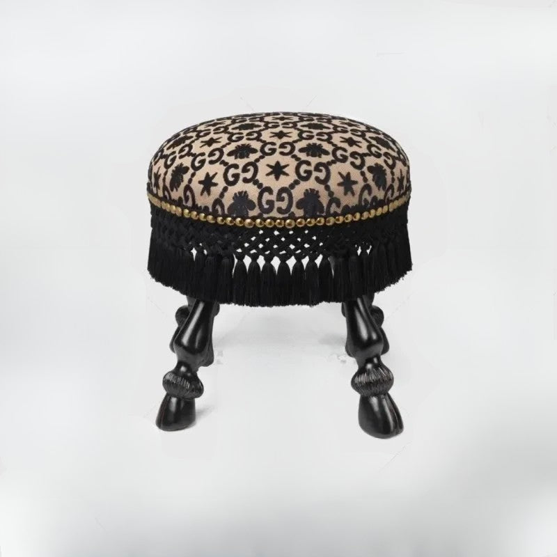 Decorative stool with leopard print top and black fringe on a white background
