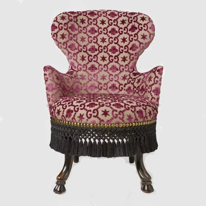 Patterned armchair with decorative fringe on a white background