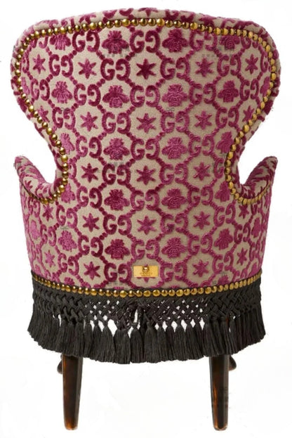 Decorative chair with pink patterned fabric and tassels on a white background