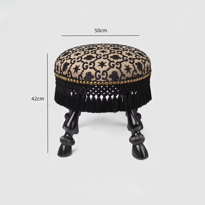 Small round stool with leopard print top and black fringes on a white background