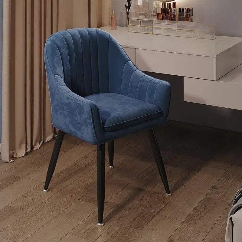 Blue velvet chair in a room with a desk and curtains