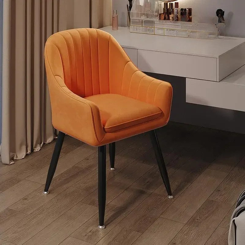 Orange chair with black legs on a wooden floor in a room setting.