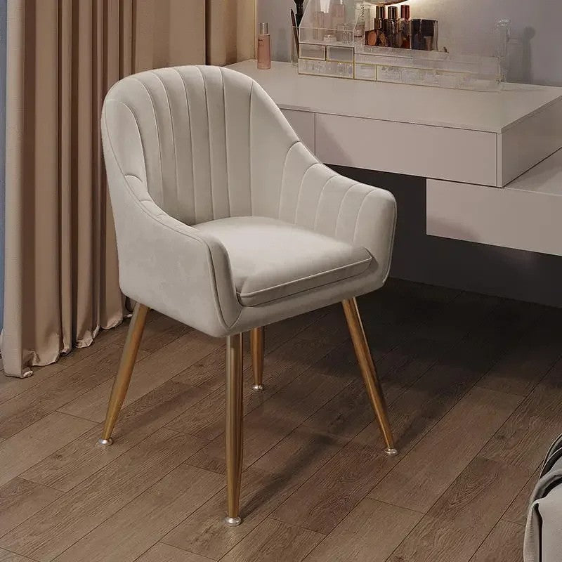 Beige armchair with gold legs on a wooden floor in a room setting.
