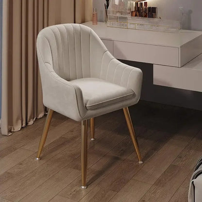 Beige armchair with gold legs on a wooden floor in a room setting.