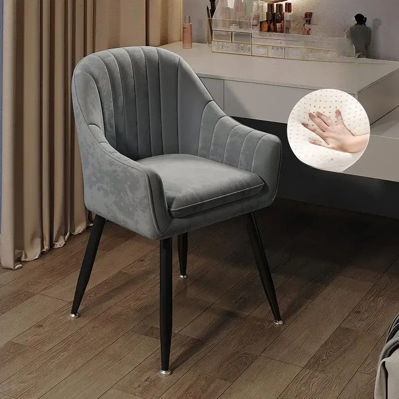 Gray velvet chair with black legs on a wooden floor, close-up of fabric texture shown.