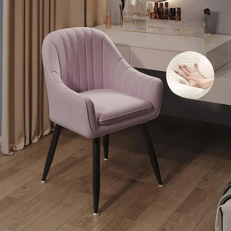 Pink velvet chair with black legs on a wooden floor, close-up of hand touch感.