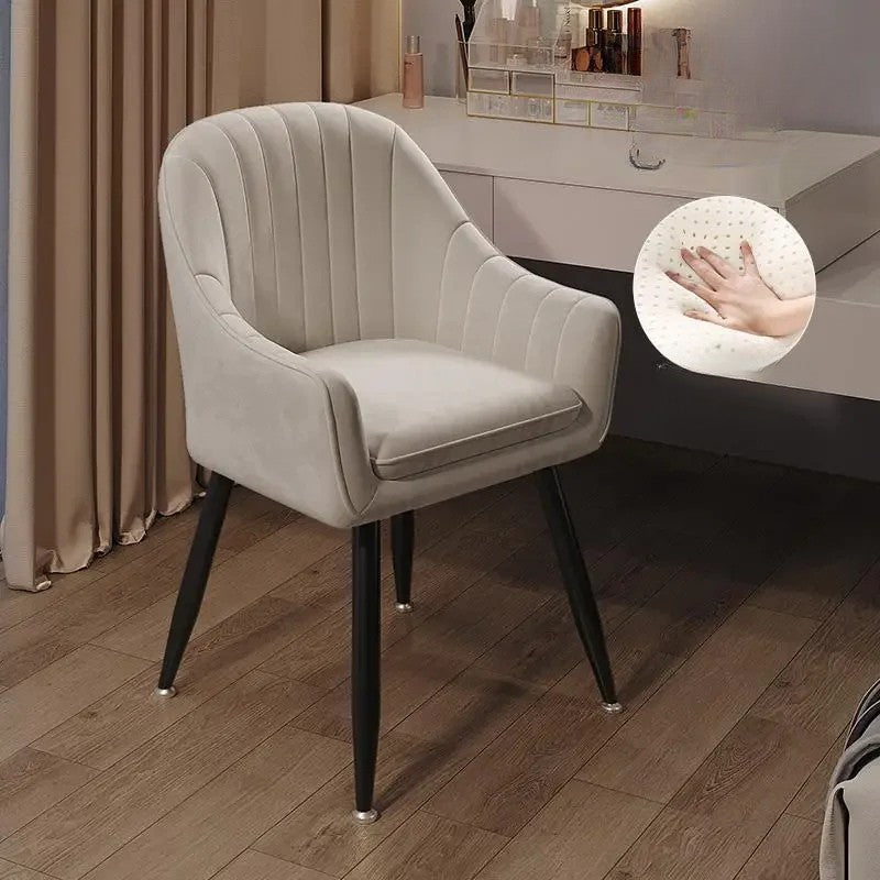 Beige armchair with black legs on a wooden floor, close-up of hand touch on fabric texture.