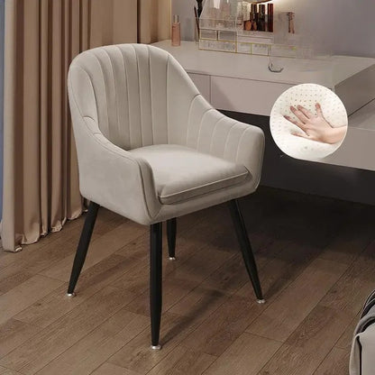 Beige armchair with black legs on a wooden floor, close-up of hand touch on fabric texture.